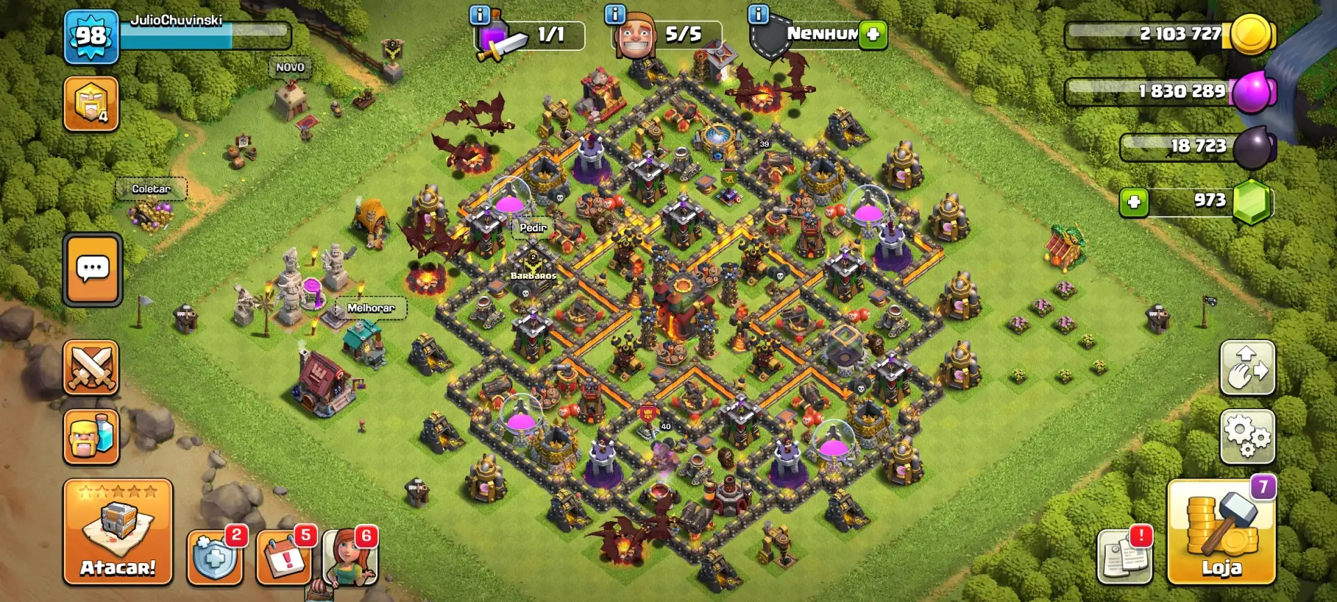 Captura de tela de uma base Clash of Clans de nível 98 (JulioChuvinski) com Centro de Vila nível 10, exibindo defesas, coletores de recursos, heróis (Rei Bárbaro, Rainha Arqueira) e dragões voando. Recursos visíveis: 2.1M Ouro, 1.8M Elixir, 18k Elixir Negro e 973 Gemas.