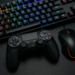 Setup gamer com teclado mecânico RGB, controle PlayStation 4 DualShock e mouse gaming em superfície escura.